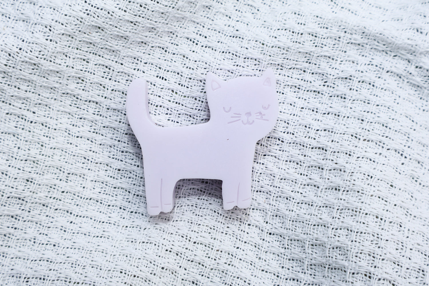 a pale purple lilac soap bar, laying against a white picnic blanket